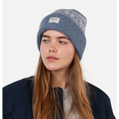 A woman wearing a Barts Denim Blue knitted Negomba beanie with a Nordic pattern, turn-up hem and logo patch on a white background