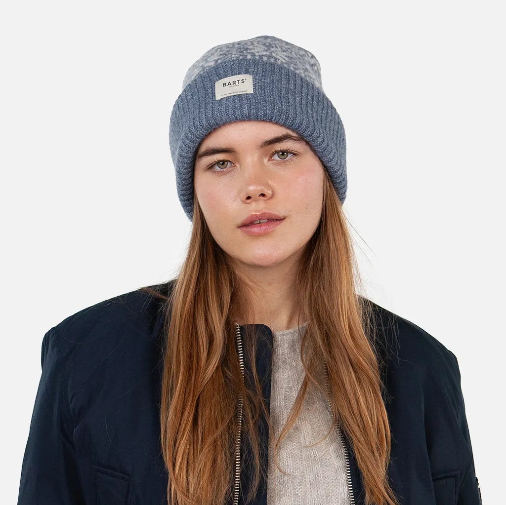 Woman wearing a Barts Negomba Denim Blue knit beanie with a Fair Isle pattern, turn-up hem and logo patch on a white background