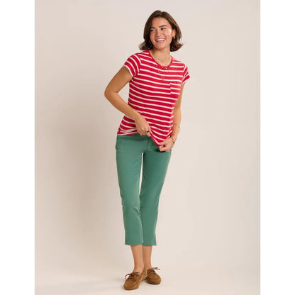 A woman wearing a Brakeburn red and white stripe Coastline short sleeve t-shirt with a pocket on the chest with turquoise capri trousers and brown shoes.