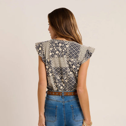 Back view of a woman wearing a Brakeburn short sleeve Salinas blouse in a cream and navy patchwork floral and geometric print
