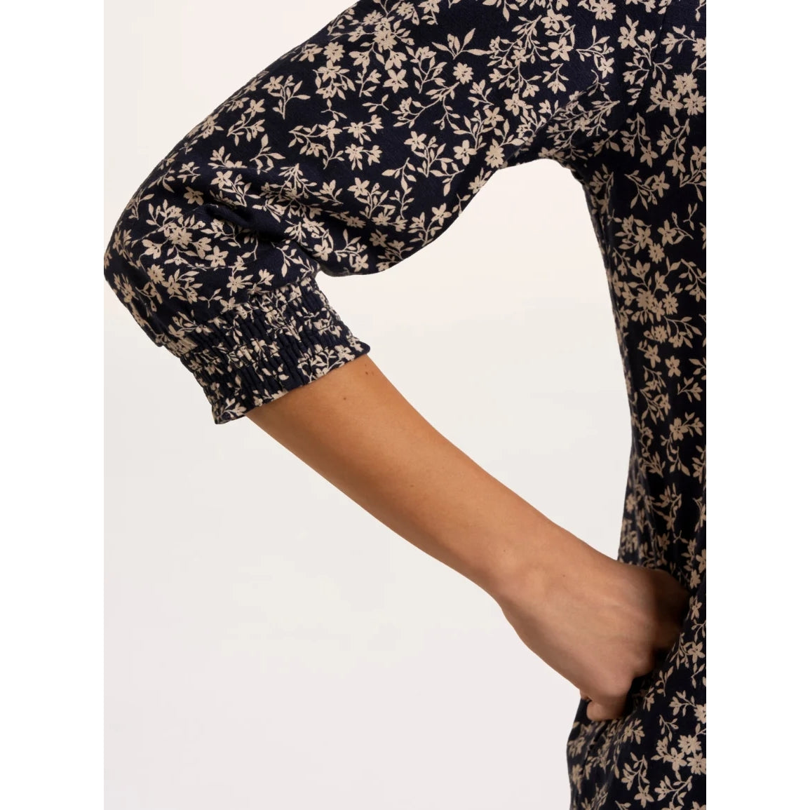 Close-up view of the elasticated 3/4 sleeve cuff of a woman wearing a Brakeburn Brielle 3/4 sleeve t-shirt in navy with a white floral pattern.