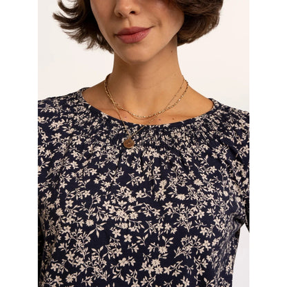 Close-up view of the neckline of a woman wearing a Brakeburn Brielle 3/4 sleeve t-shirt in navy with a white floral pattern and elasticated neckline trim.
