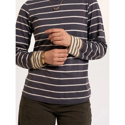 Close-up view of a woman wearing a Brakeburn long sleeve Exbury t-shirt in light navy with white stripes and contrasting mustard stripe cuffs.