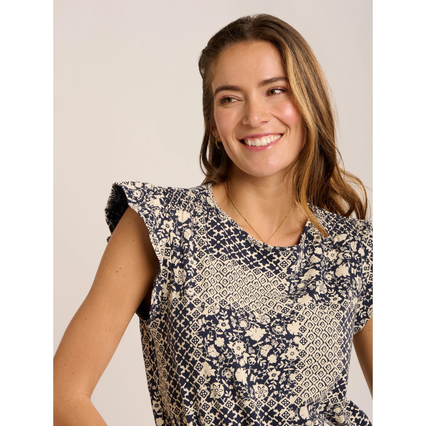 Close-up view of a woman wearing a Brakeburn short sleeve Salinas blouse in a cream and navy patchwork floral and geometric print