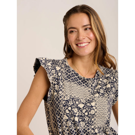 Close-up view of a woman wearing a Brakeburn short sleeve Salinas blouse in a cream and navy patchwork floral and geometric print