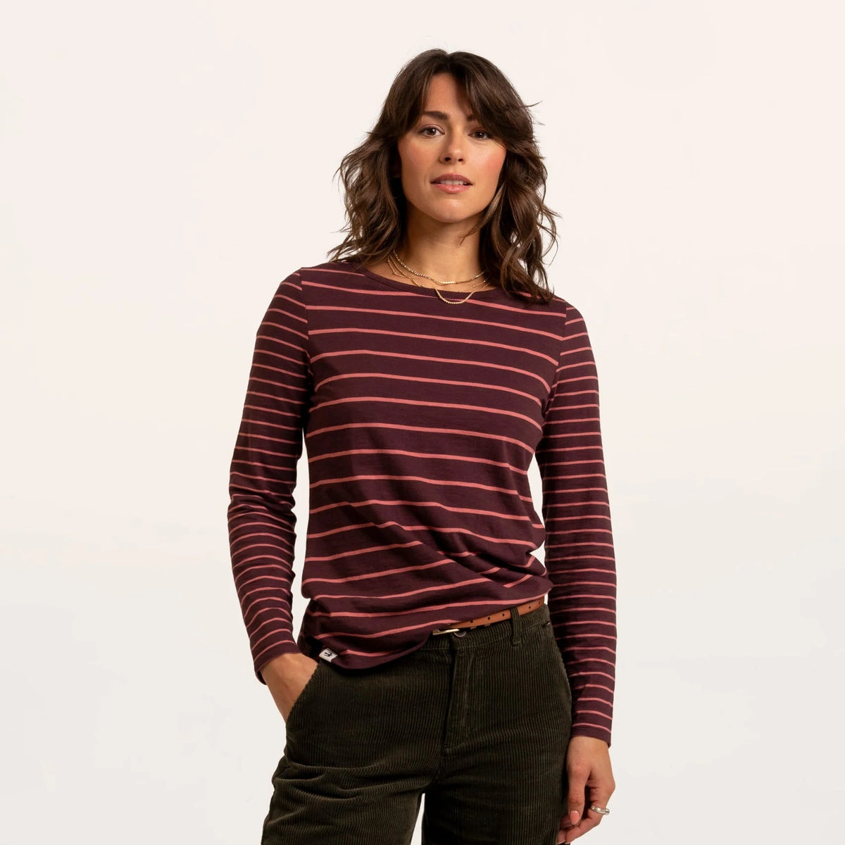 Front view of a woman wearing a Brakeburn long sleeve thick and thin stripe Branksome t-shirt in burgundy with coral stripes.