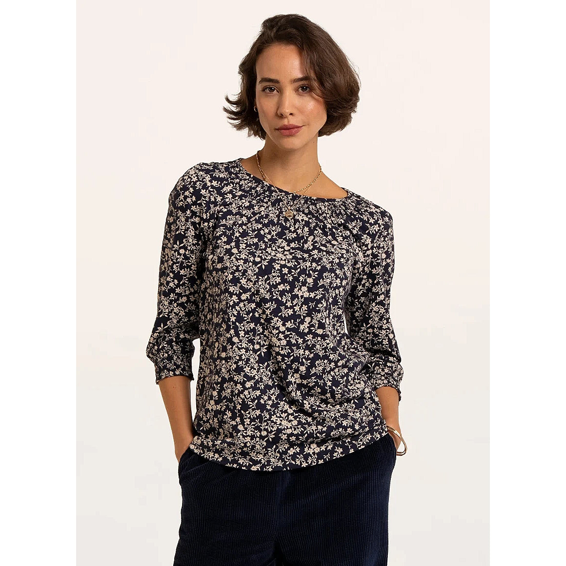 Front view of a woman wearing a Brakeburn Brielle 3/4 sleeve t-shirt in navy with a white floral pattern and elasticated cuffs and neckline trim.