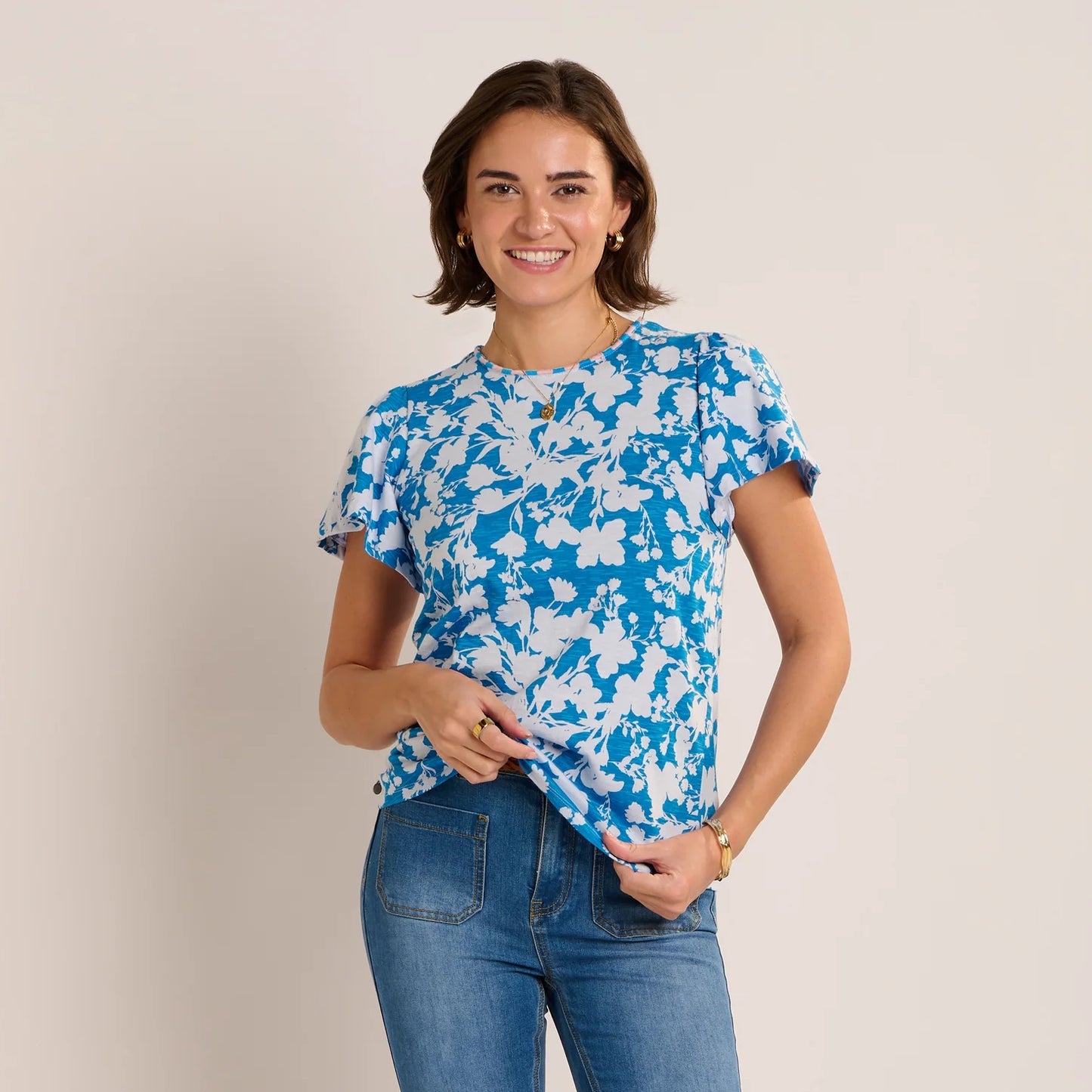 Front view of a woman wearing a Brakeburn short sleeve Ria blouse in blue with a white floral print.