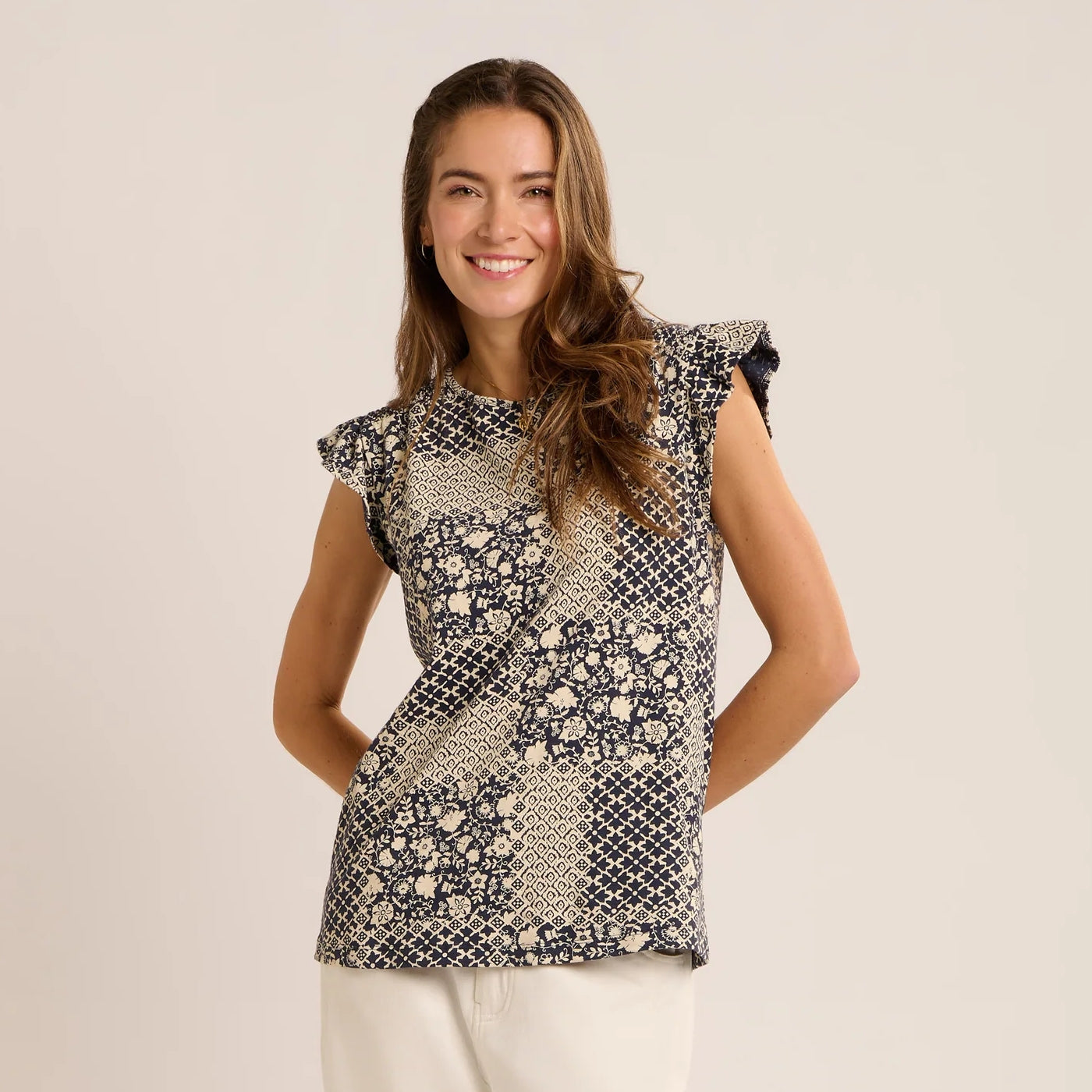 Front view of a woman wearing a Brakeburn short sleeve Salinas blouse in a cream and navy patchwork floral and geometric print