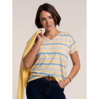 Woman wearing a Brakeburn short sleeve v-neck Seas t-shirt in a blue and yellow stripe pattern, with navy trousers and yellow cardigan.
