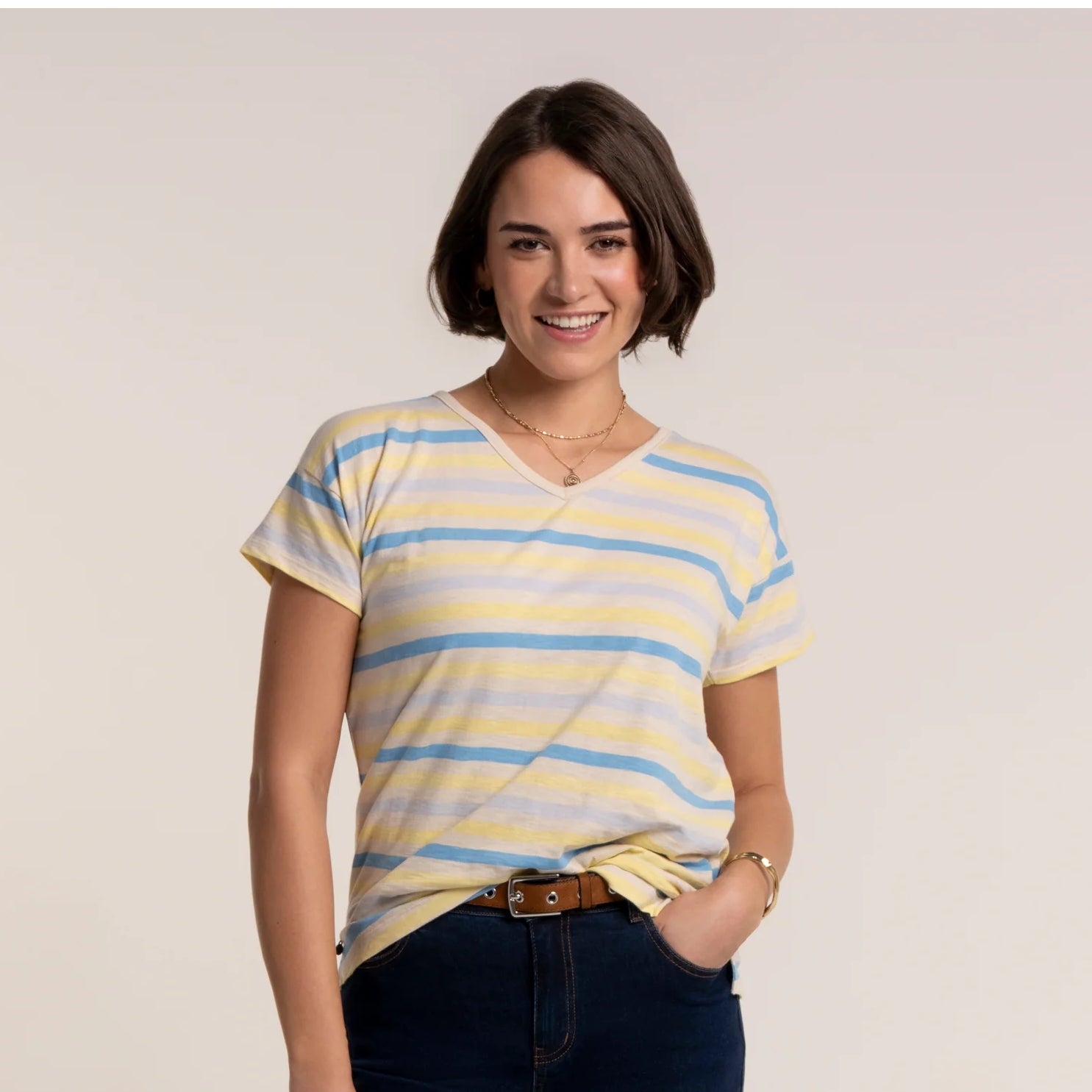 Front view of a woman wearing a Brakeburn short sleeve Seas t-shirt in a blue and yellow stripe pattern, with v-shape neckline.