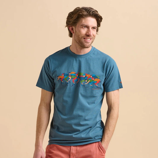 Front view of a man wearing a Brakeburn blue t-shirt with colourful Painted Peleton cyclist print design on a beige background