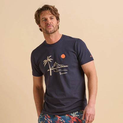 Front view of a man wearing a navy blue Island t-shirt with a palm tree and mountain graphic on a beige background