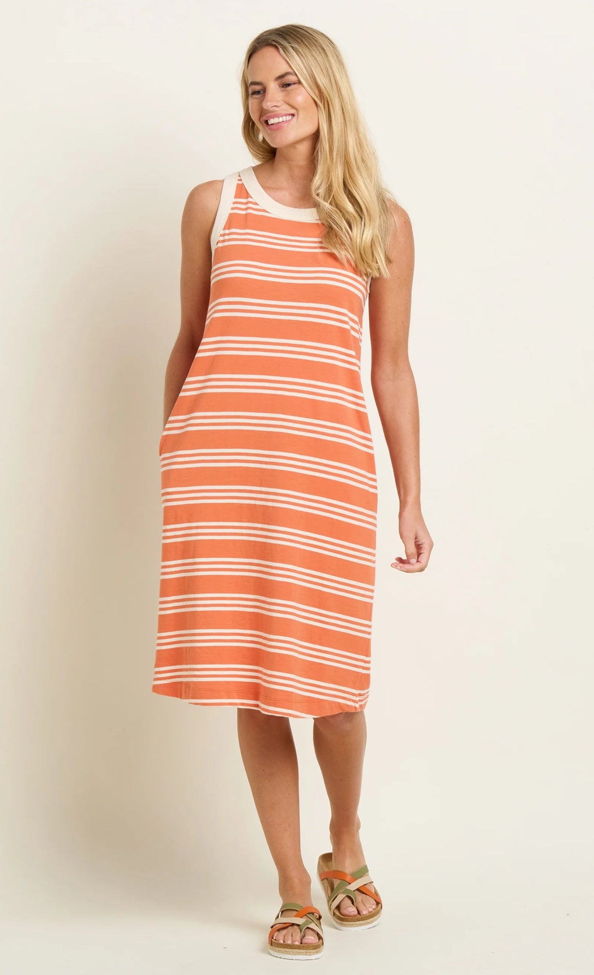 Brakeburn sleeveless stripe dress in orange and white worn by smiling woman with sandals