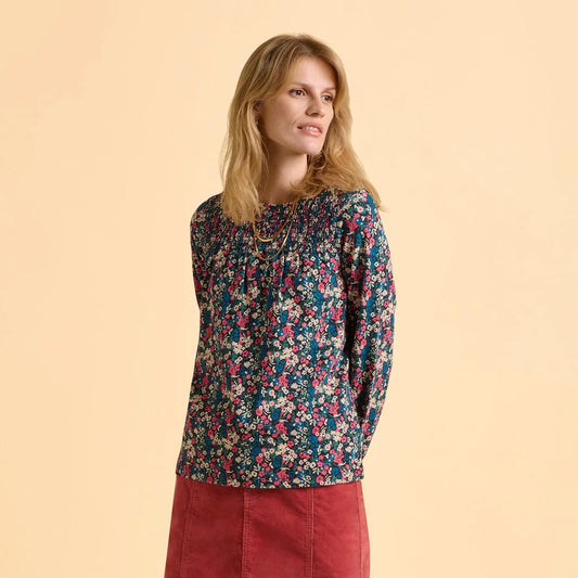 Front view of a woman wearing a Brakeburn Brenda floral long sleeve t-shirt and a red skirt on a beige background
