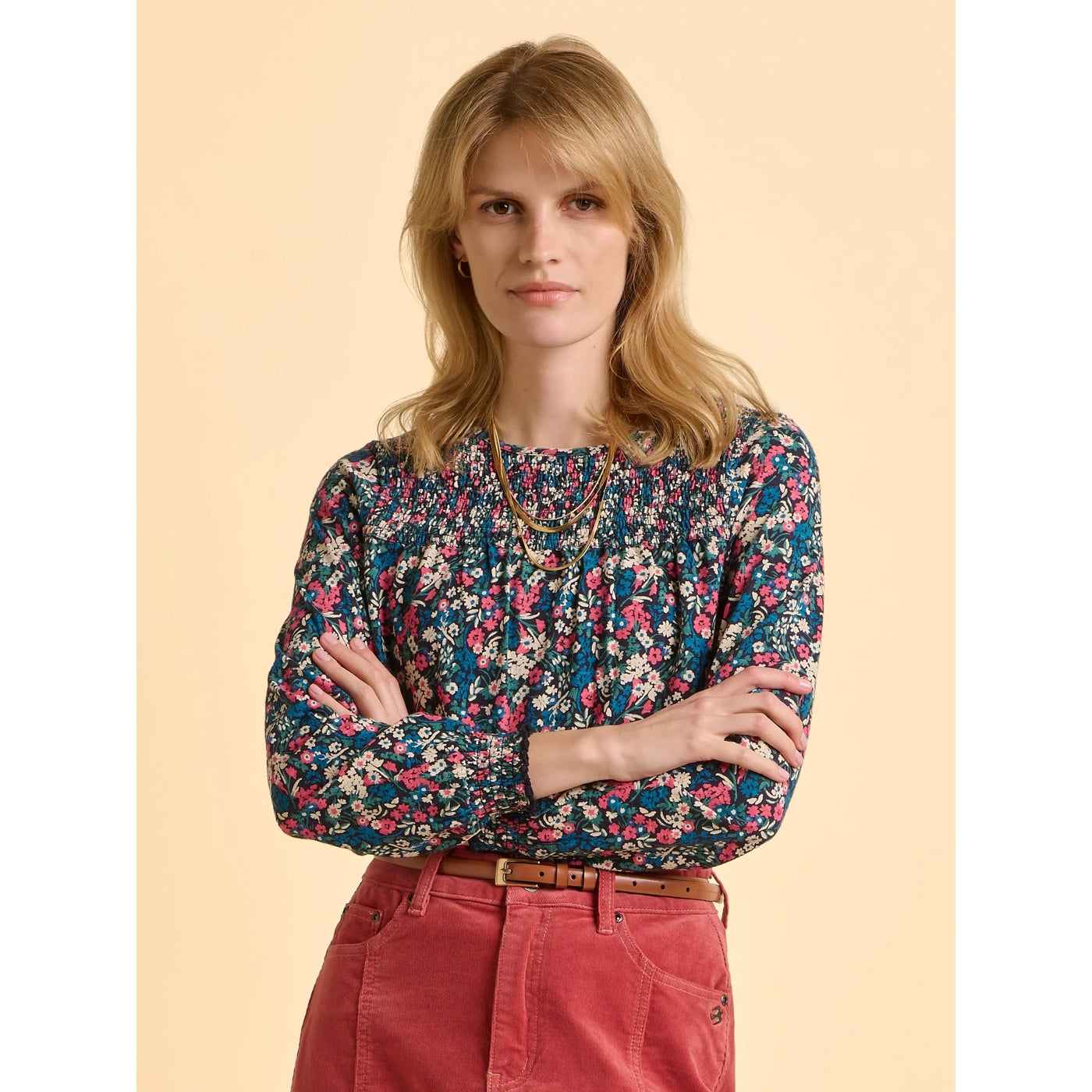 Front view of a woman wearing a multicolour floral Brakeburn long sleeve Brenda t-shirt and red skirt against a beige background