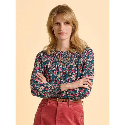 Front view of a woman wearing a multicolour floral Brakeburn long sleeve Brenda t-shirt and red skirt against a beige background
