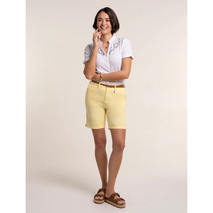 A woman wearing a pair of Brakeburn chino shorts in a soft yellow shade with a white blouse.
