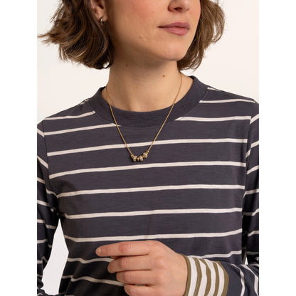 Close-up view of a woman wearing a Brakeburn long sleeve Exbury t-shirt in light navy with white stripes and contrasting mustard coloured stripe cuffs.