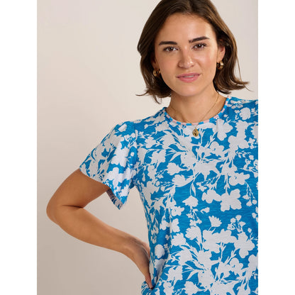 Close-up view of a woman wearing a Brakeburn short sleeve Ria blouse in blue with a white floral print and pink and blue stripe neckline.