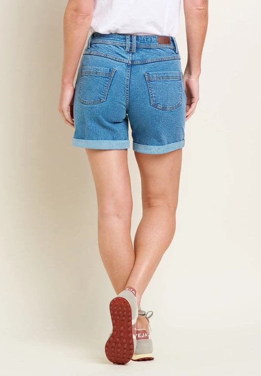 Brakeburn womens denim shorts in blue with rolled hems shown from the back on a model