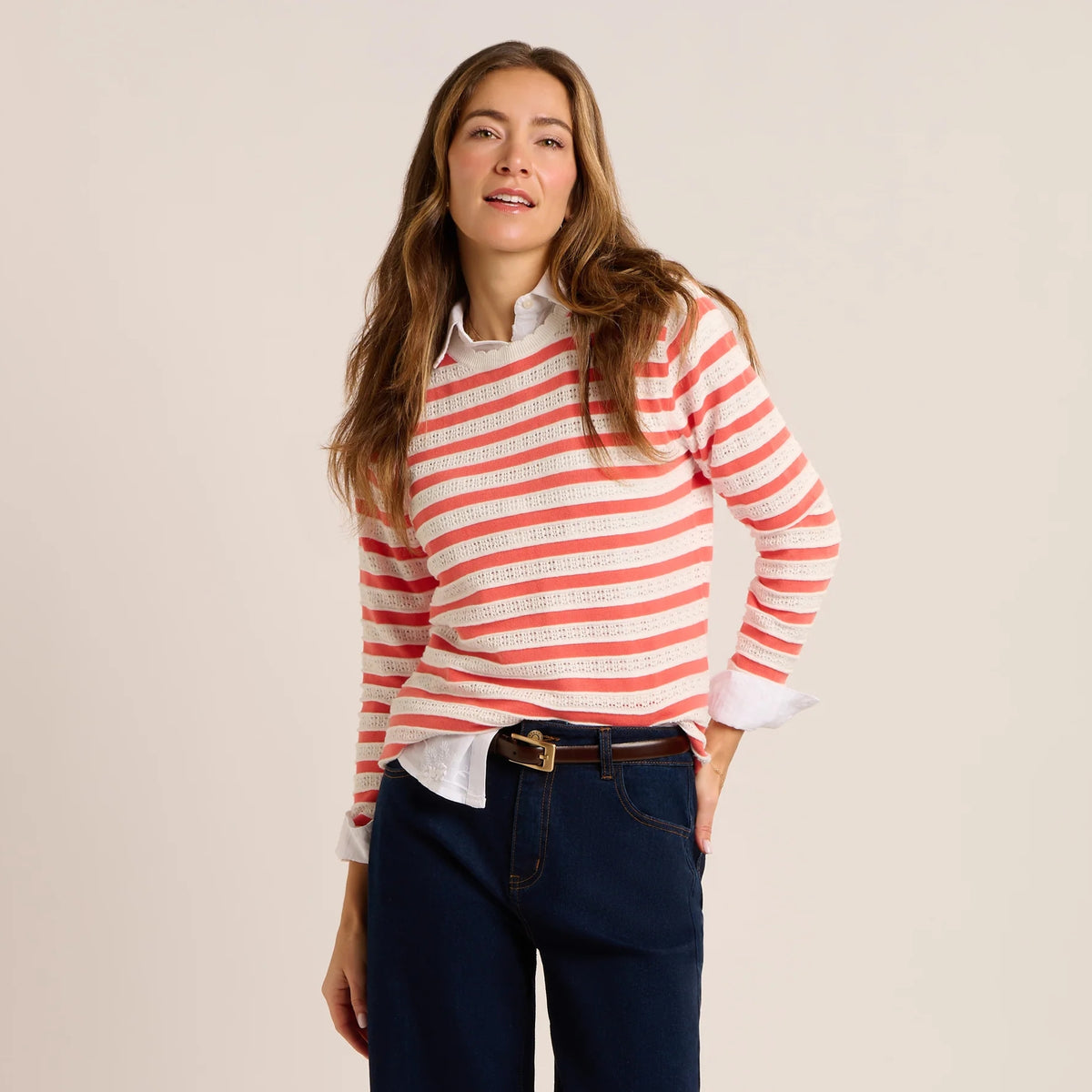 Front view of a woman wearing a Brakeburn Revelle fine knit jumper in coral and white stripe with scalloped detail.