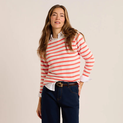 Front view of a woman wearing a Brakeburn Revelle fine knit jumper in coral and white stripe with scalloped detail.