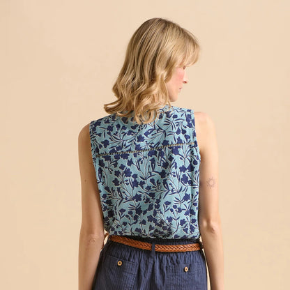 Back view of a woman wearing a Brakeburn sleeveless blue floral vest top on a beige background
