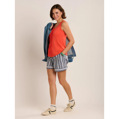 Side view of a woman wearing a pair of Brakeburn loose fit Lettie beach shorts in Navy with a white vertical stripe pattern with an elastic waist.