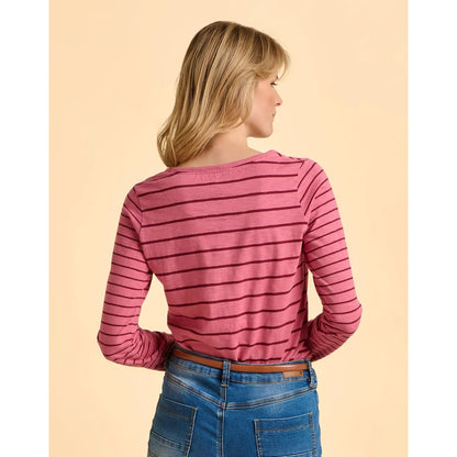 Woman wearing a pink striped long-sleeve shirt and blue jeans on a beige background