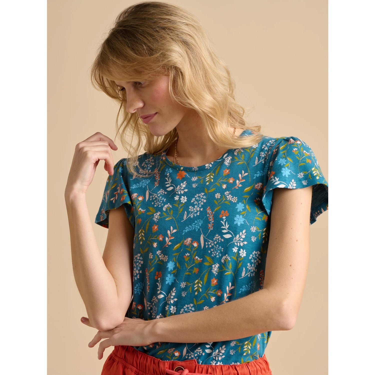 Woman wearing a Brakeburn teal floral meadow t-shirt against a beige background