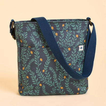 Back view of a Brakeburn Twilight Leaves cross body bag with floral leaf pattern and a blue strap on a beige background 