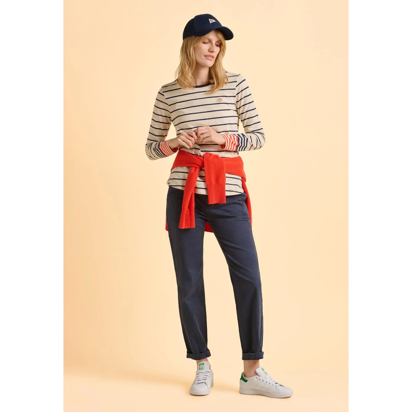Woman wearing a striped Brakeburn cream Knoll t-shirt and navy pants on a beige background