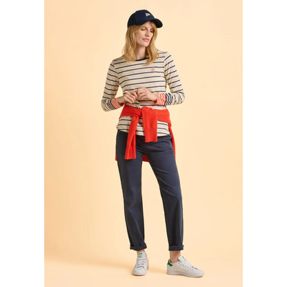 Woman wearing a striped Brakeburn cream Knoll t-shirt and navy pants on a beige background