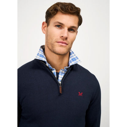 Close-upp view of a man wearing a Crew Clothing 1/4 zip classic knitted jumper in Heritage Navy with small red crossed oars logo on the chest