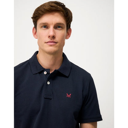 Close-up view of a mens Crew Clothing short sleeve classic pique polo shirt in Heritage Dark Navy with small crossed oars logo on the chest
