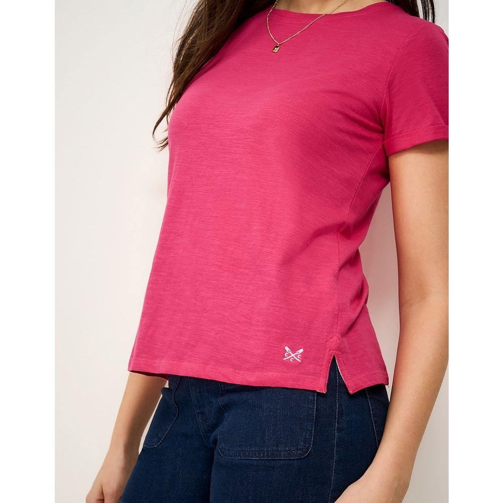 Woman wearing a Crew Clothing Perfect short sleeve plain t-shirt in raspberry pink with small embroidered logo by the hem and side seam slits