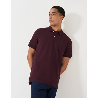 Front view of a man wearing a Crew Clothing short sleeve classic pique polo shirt in Heritage Burgundy with small crossed oars logo on the chest