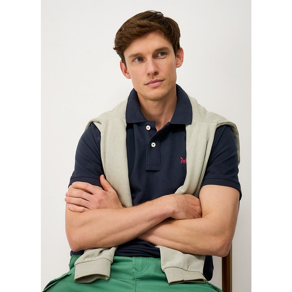Front view of a man wearing a Crew Clothing short sleeve classic pique polo shirt in Heritage Dark Navy with small crossed oars logo on the chest