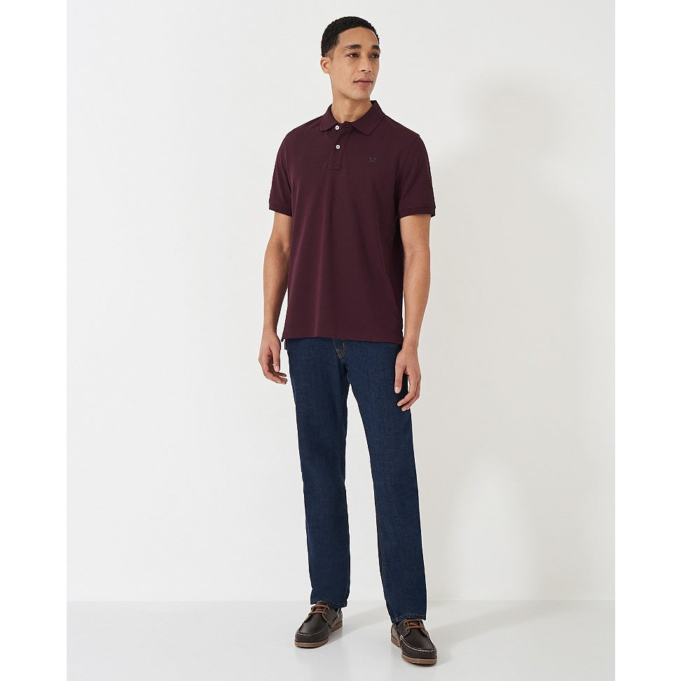 Man wearing a Crew Clothing short sleeve classic pique polo shirt in Heritage Burgundy with jeans