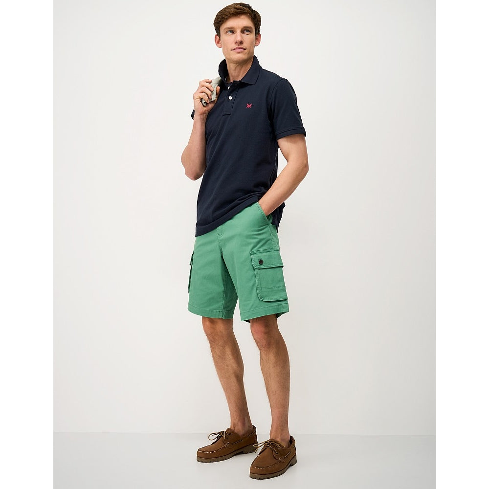 Man wearing a Crew Clothing short sleeve classic pique polo shirt in Heritage Dark Navy with green shorts