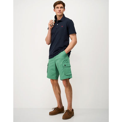 Man wearing a Crew Clothing short sleeve classic pique polo shirt in Heritage Dark Navy with green shorts