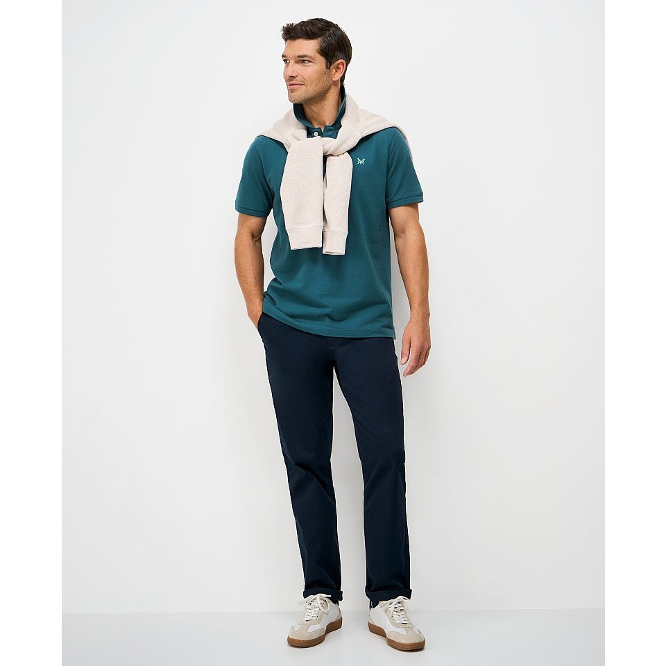 Man wearing a Crew Clothing short sleeve classic pique polo shirt in Teal with jeans and trainers
