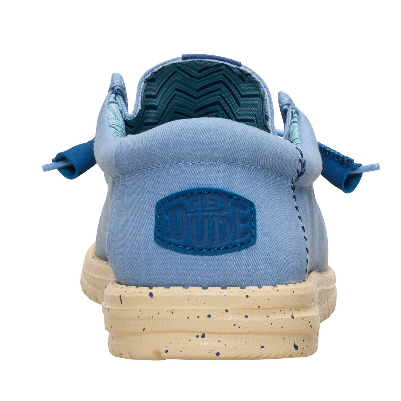 Back heel view of a men's Dude Wally Stretch Canvas lightweight shoe in Faded Denim Blue / Boulder Tan, with elastic laces, a speckled sole and Hey Dude patch sewn on the heel.