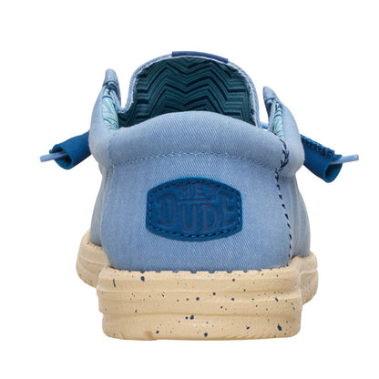 Back heel view of a men's Dude Wally Stretch Canvas lightweight shoe in Faded Denim Blue / Boulder Tan, with elastic laces, a speckled sole and Hey Dude patch sewn on the heel.