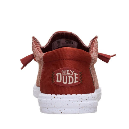 Back heel view of a men's Dude Wally Stretch Sox lightweight mesh shoe in Burnt Red / Multi, with elastic laces, a white speckled sole and plain blue back panel with Hey Dude logo.