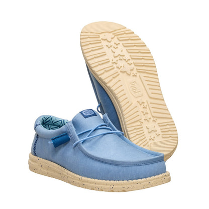 A pair of men's Dude Wally Stretch Canvas lightweight shoes in Faded Denim Blue / Boulder Tan, with elastic laces, with one shoe upside down showing the EVA outsole.