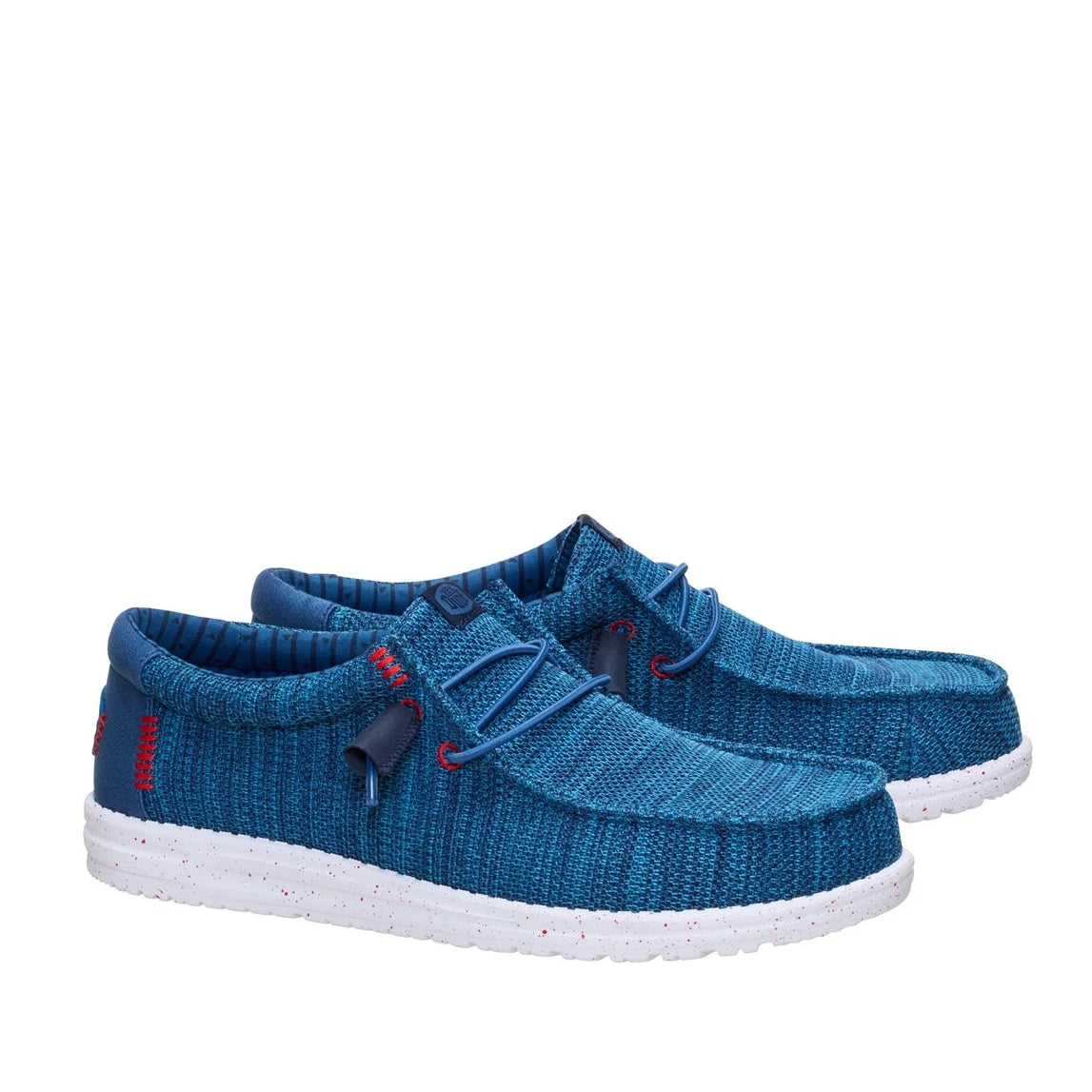 A pair of men's Dude Wally Stretch Sox shoes in Ensign Blue with white speckled soles, elastic laces and red stitching accents.