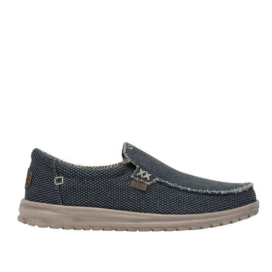 Side view of a men's Dude Mikka Braided lightweight slip on canvas shoe in Deep Blue with side logo label.