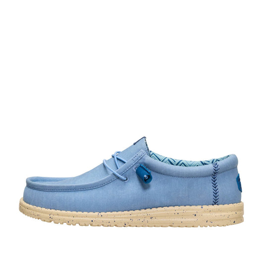 Side view of a men's Dude Wally Stretch Canvas lightweight shoe in Faded Denim Blue / Boulder Tan, with elastic laces and a speckled sole.